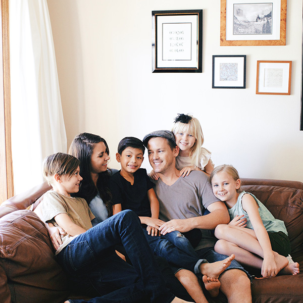 A family sitting on a couch and hugging and smiling