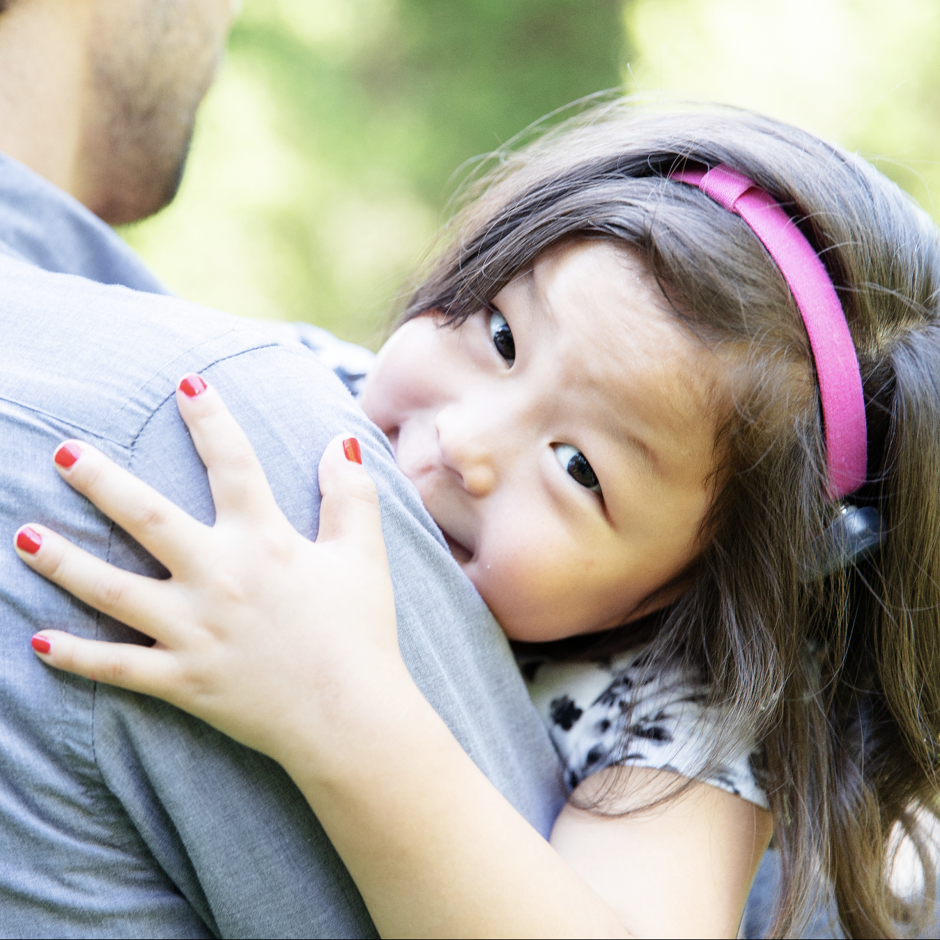 A girl being held by her dad and looking past his shoulder for a picture