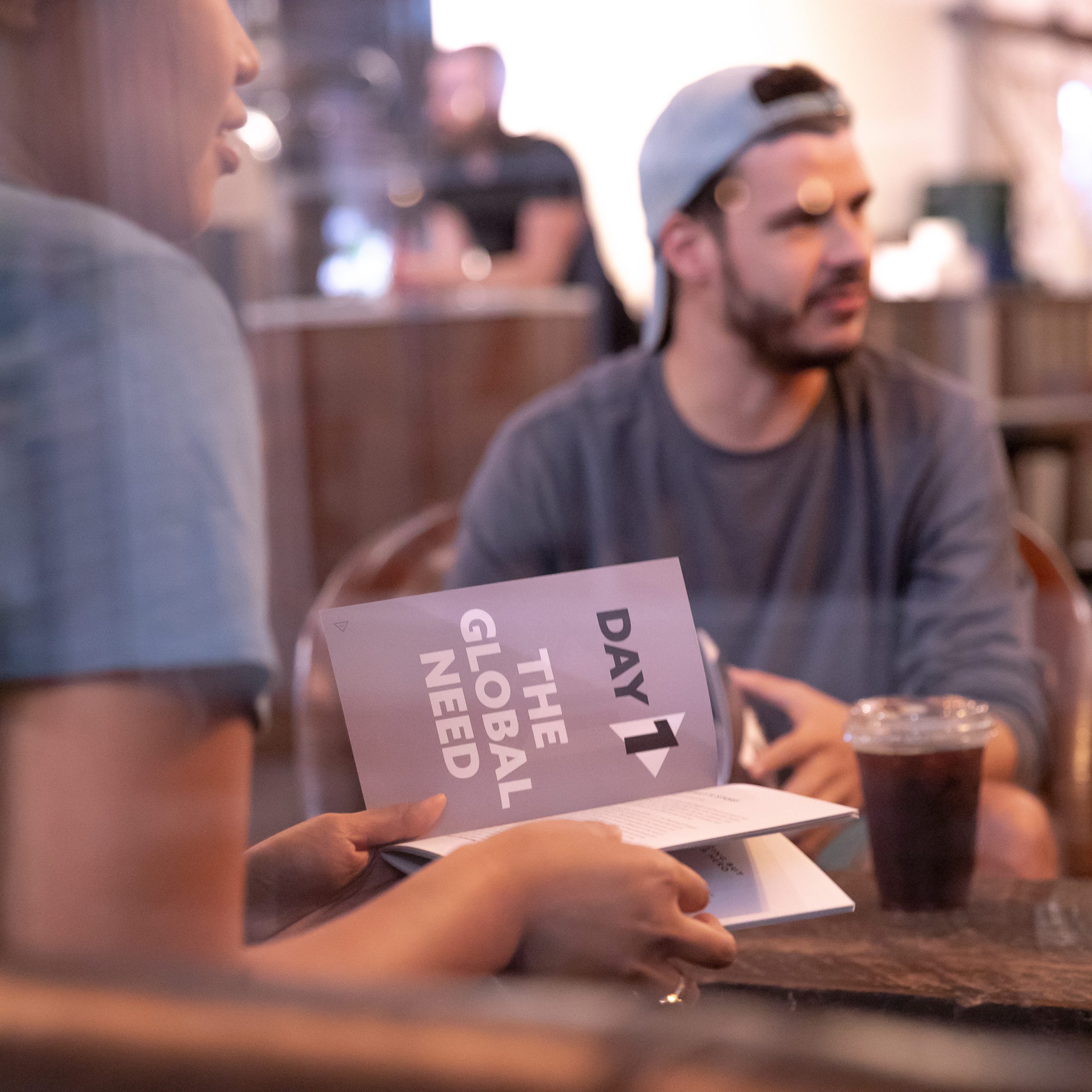 Young adults reading the Pause Campaign booklet in a coffee shop