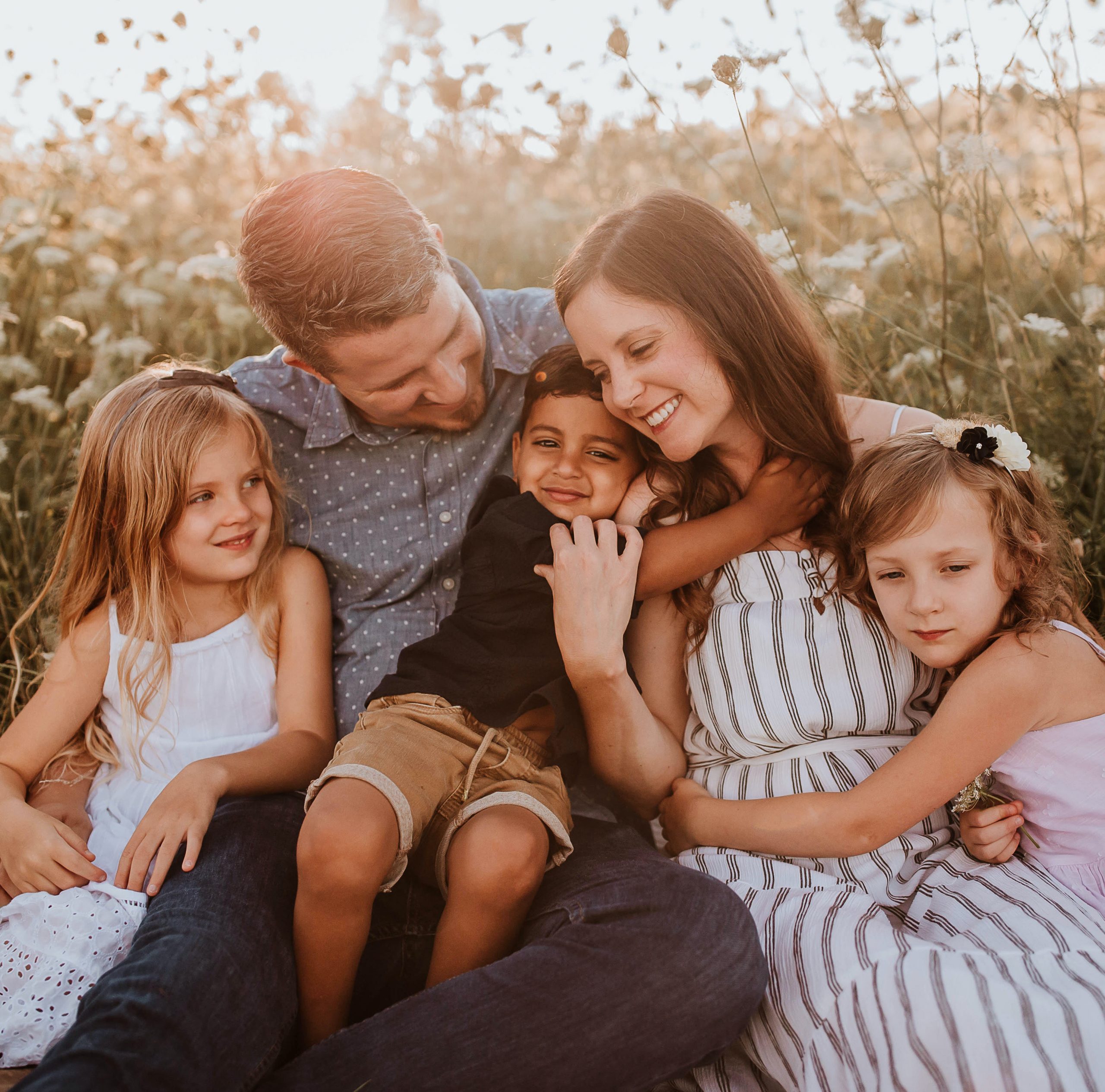 Adoption Aid Grant family, the Mackeys, all sitting outside and hugging each other while smiling.