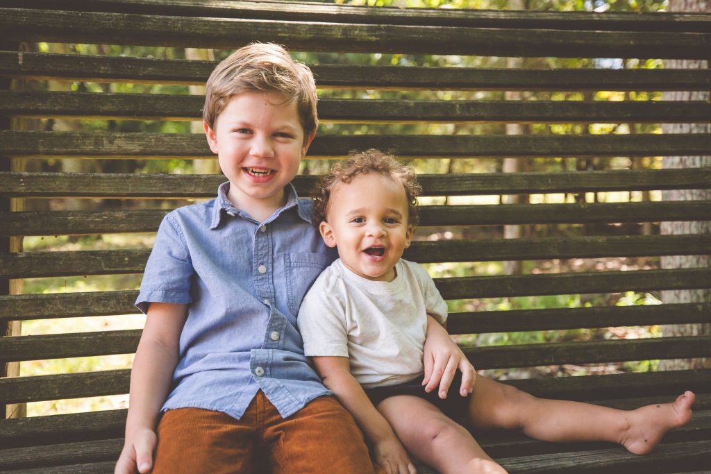 Meet the Haglers | An image of two young boys hugging, smiling, and sitting on a bench