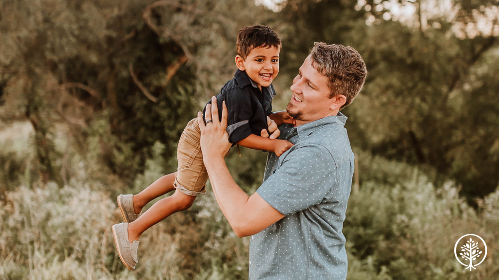 Dad who received a Show Hope Adoption Aid grant holding his son smiling at camera 