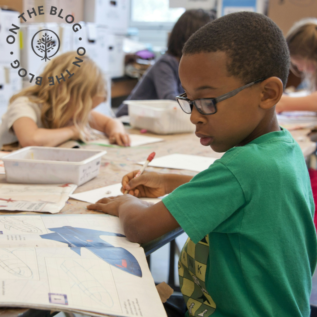 Boy writing on paper sitting in a classroom