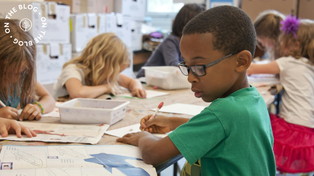 Boy writing on paper sitting in a classroom